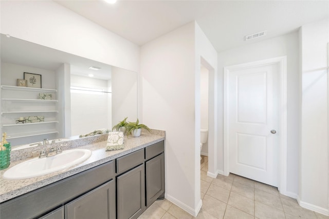 bathroom featuring vanity, baseboards, visible vents, tile patterned flooring, and toilet