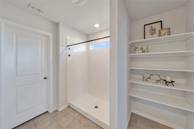 full bath featuring tile patterned floors, baseboards, visible vents, and tiled shower