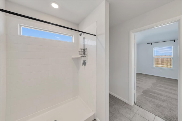 bathroom featuring a tile shower, plenty of natural light, tile patterned flooring, and baseboards