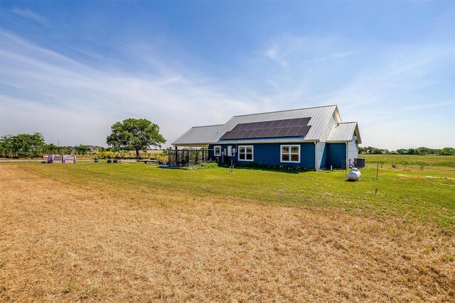 exterior space featuring roof mounted solar panels, a lawn, and metal roof