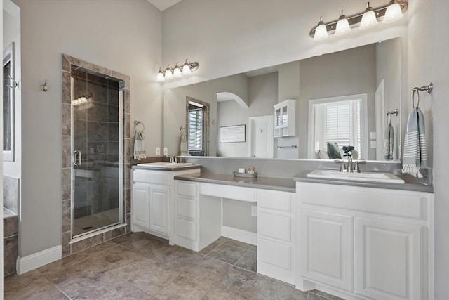 bathroom with a sink, a stall shower, and double vanity