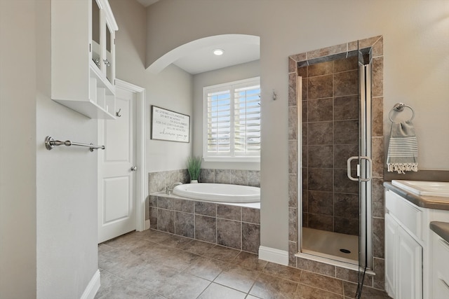 full bathroom featuring vanity, a bath, a stall shower, and tile patterned flooring