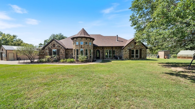 french country home with stone siding, an outdoor structure, and a front lawn