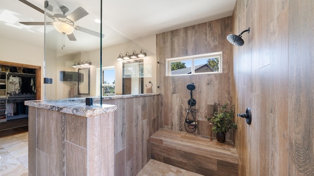 bathroom with ceiling fan, a spacious closet, and walk in shower