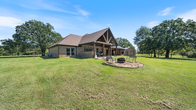 back of property with a patio, a lawn, brick siding, and an outdoor fire pit