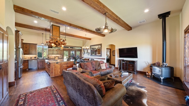 living room featuring dark wood-style floors, visible vents, a wood stove, arched walkways, and beamed ceiling