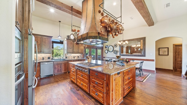 kitchen featuring backsplash, light stone counters, island range hood, stainless steel appliances, and dark wood-style flooring