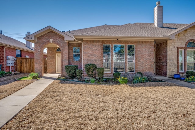 ranch-style house with brick siding, a chimney, a front lawn, and a shingled roof