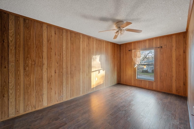 empty room featuring a ceiling fan, wooden walls, wood finished floors, and a textured ceiling