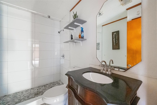 bathroom featuring vanity, toilet, visible vents, and a tile shower