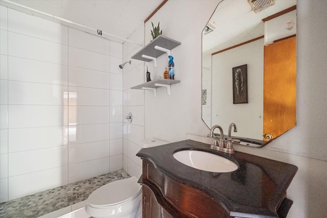 bathroom with vanity, toilet, visible vents, and tiled shower