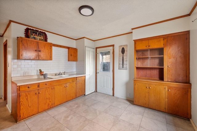 kitchen with a sink, brown cabinets, ornamental molding, and light countertops