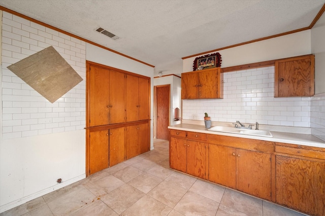 kitchen with visible vents, brown cabinets, light countertops, and a sink