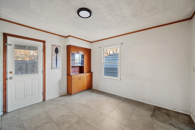 spare room with a textured ceiling, baseboards, and ornamental molding