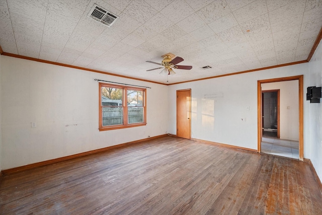 spare room featuring visible vents, ornamental molding, baseboards, and wood finished floors