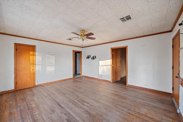 spare room featuring visible vents, crown molding, baseboards, and wood finished floors