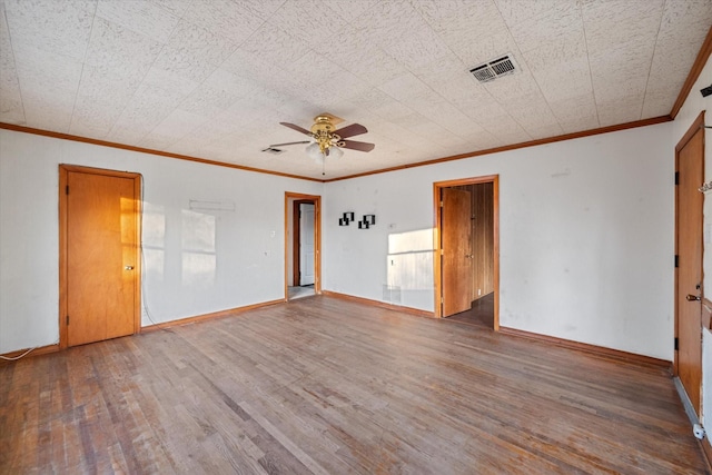 spare room featuring a ceiling fan, wood finished floors, visible vents, baseboards, and crown molding