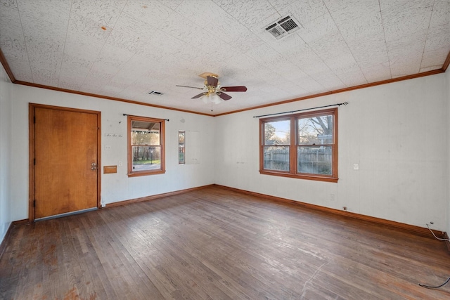 spare room featuring hardwood / wood-style floors, a ceiling fan, baseboards, visible vents, and ornamental molding