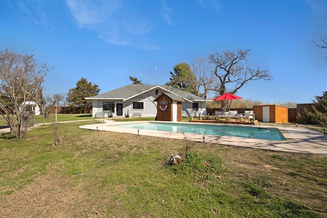 outdoor pool with an outbuilding, a patio, a storage shed, and a yard