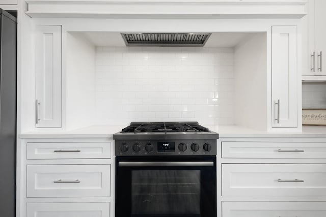 kitchen with black range with gas cooktop, decorative backsplash, white cabinets, and light countertops