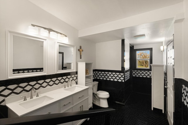 bathroom with tile walls, a wainscoted wall, and a sink