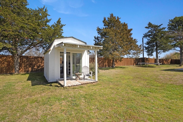 view of yard featuring an outbuilding, a trampoline, and a fenced backyard