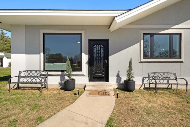 property entrance with a yard and stucco siding