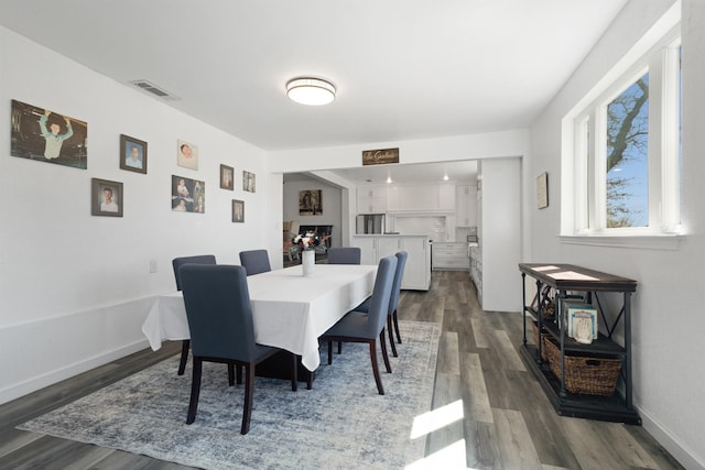 dining room with dark wood finished floors, visible vents, and baseboards