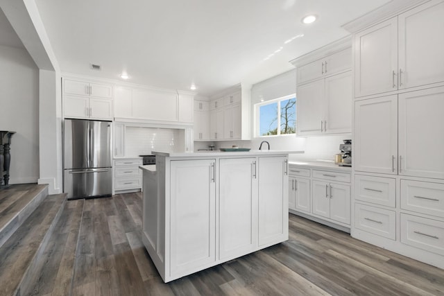 kitchen with visible vents, tasteful backsplash, freestanding refrigerator, white cabinets, and light countertops