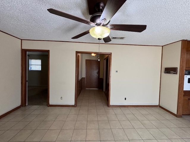 spare room with visible vents, ornamental molding, a textured ceiling, light tile patterned floors, and ceiling fan