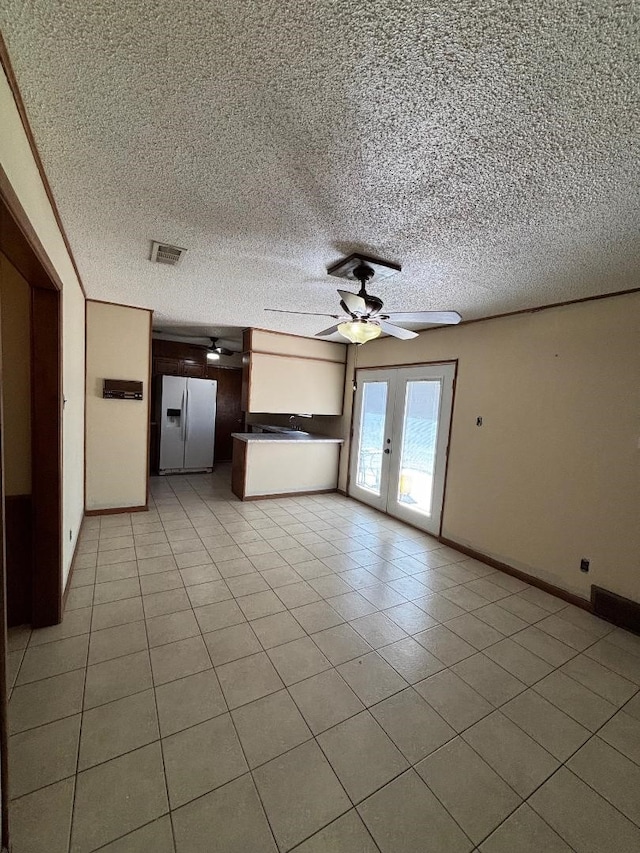 unfurnished living room with light tile patterned floors, french doors, a textured ceiling, and a ceiling fan