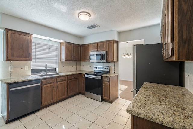 kitchen featuring light stone countertops, visible vents, a sink, stainless steel appliances, and backsplash