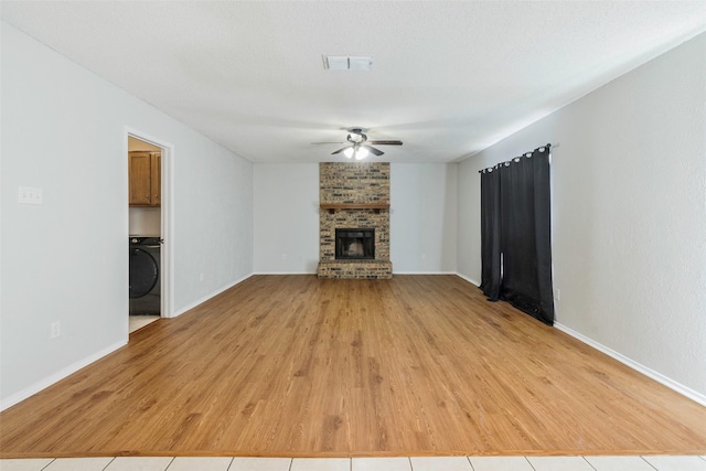 unfurnished living room featuring visible vents, wood finished floors, baseboards, a brick fireplace, and ceiling fan