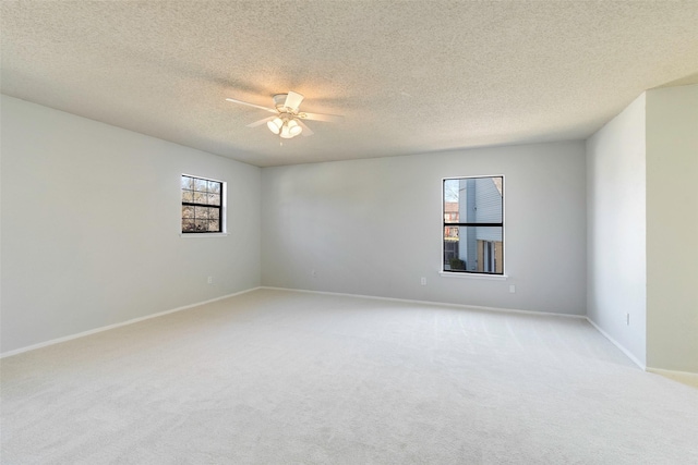 empty room with plenty of natural light, light colored carpet, baseboards, and ceiling fan