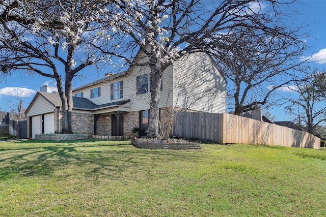 traditional-style home with a front yard, fence, brick siding, and a garage