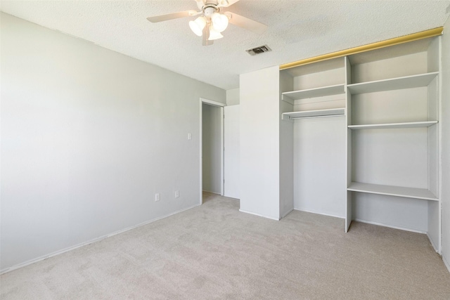 unfurnished bedroom featuring visible vents, carpet floors, ceiling fan, a closet, and a textured ceiling