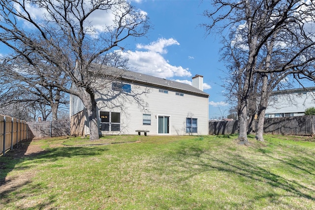 back of house featuring a lawn, a fenced backyard, and a chimney