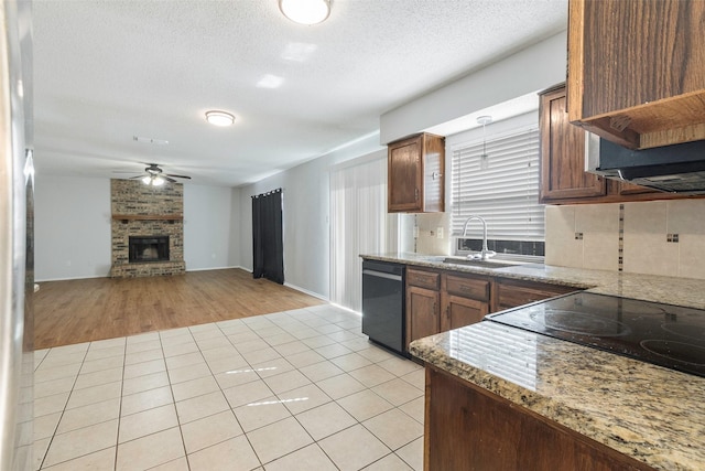 kitchen with a sink, a brick fireplace, dishwasher, and light tile patterned floors