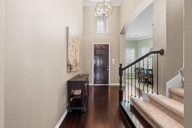 foyer entrance with stairway, wood-type flooring, crown molding, baseboards, and a textured wall