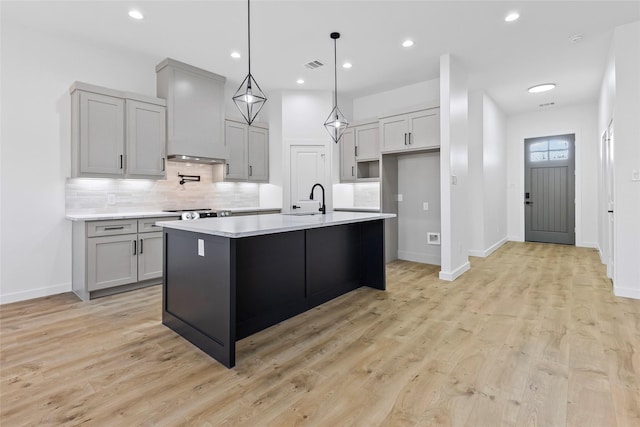 kitchen featuring visible vents, custom exhaust hood, a sink, decorative backsplash, and light countertops