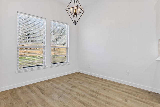 unfurnished dining area featuring a notable chandelier, baseboards, and light wood finished floors