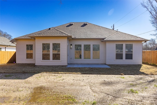 back of house with a patio area, roof with shingles, and fence