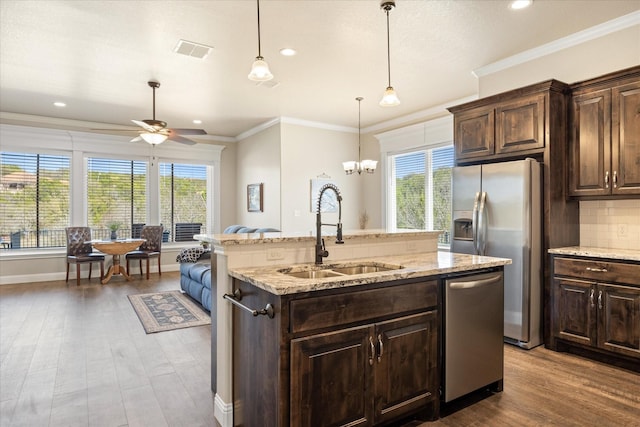 kitchen featuring visible vents, a sink, stainless steel appliances, crown molding, and decorative backsplash