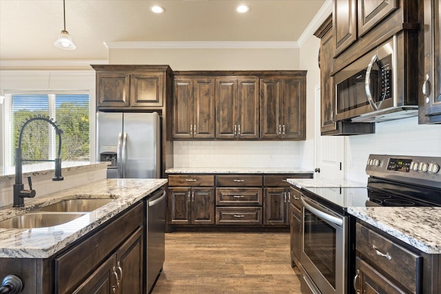 kitchen with dark wood-style floors, ornamental molding, a sink, dark brown cabinetry, and appliances with stainless steel finishes