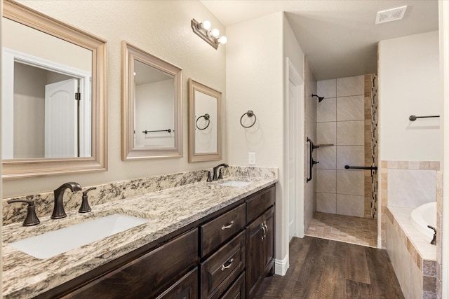 bathroom with double vanity, wood finished floors, visible vents, and a sink