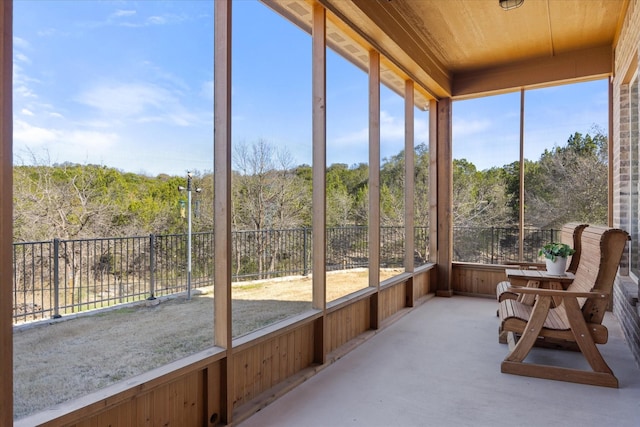 unfurnished sunroom with wood ceiling and a view of trees