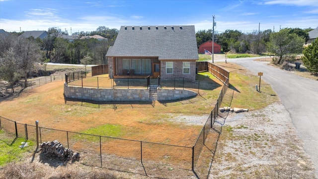 rear view of house with a shingled roof, fence, brick siding, and a lawn