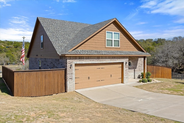 view of side of home with driveway, fence, a shingled roof, a garage, and brick siding