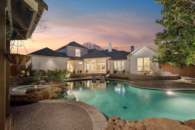 view of swimming pool with a patio area, a pool with connected hot tub, and fence