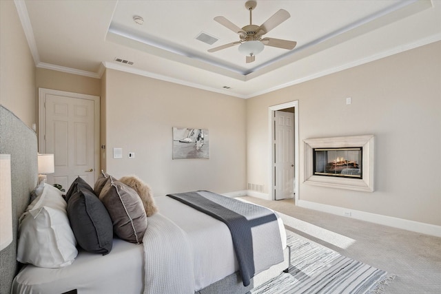 carpeted bedroom featuring visible vents, a raised ceiling, baseboards, and ornamental molding